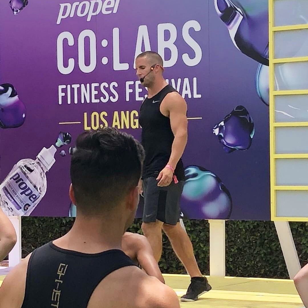 Grant Weeditz on stage with a headset microphone, leading the audience at Propel CO:LABS Los Angeles